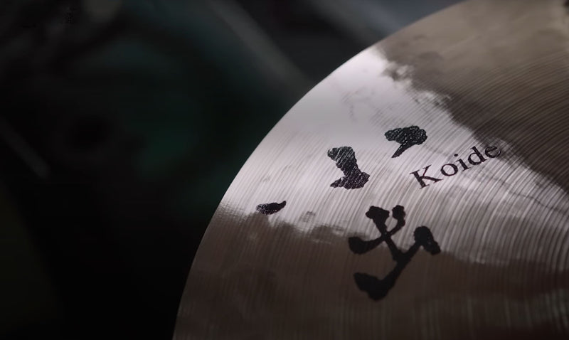 Koide cymbals displayed in a close-up shot, showcasing their handcrafted, textured surface with a natural, unlathed finish in a warm studio environment.